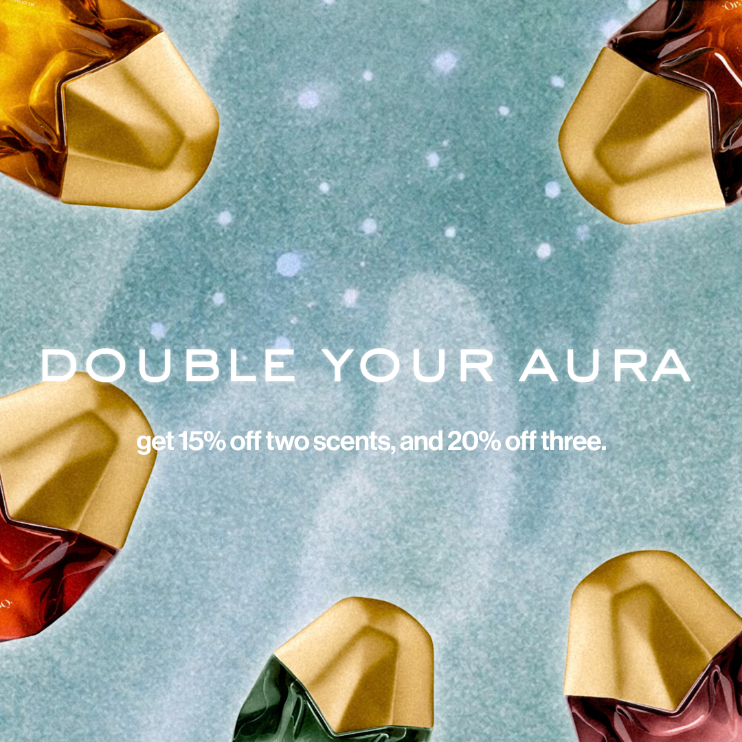 Promotional graphic for Aura scents with the text 'DOUBLE YOUR AURA' and 'get 15% off two scents, and 20% off three.' on a textured light blue background, surrounded by abstract faceted gem-like shapes in gold, amber, burgundy, and green.