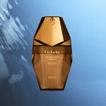 A faceted metallic gold perfume bottle labeled 'Orbella Vanilla's Touch' centered against a blue gradient background with soft light streaks.