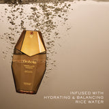 Orabella Vanilla's Touch perfume bottle floating in water with bubbles around it, set against a warm beige background with text reading 'INFUSED WITH HYDRATING & BALANCING RICE WATER'.